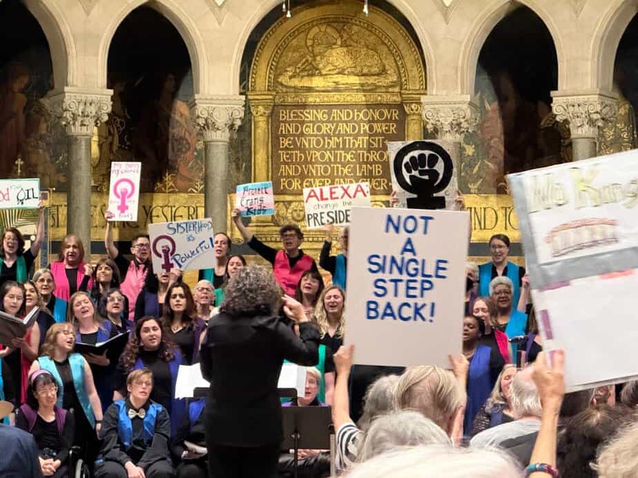 Singers on stage and audience members holding protest signs